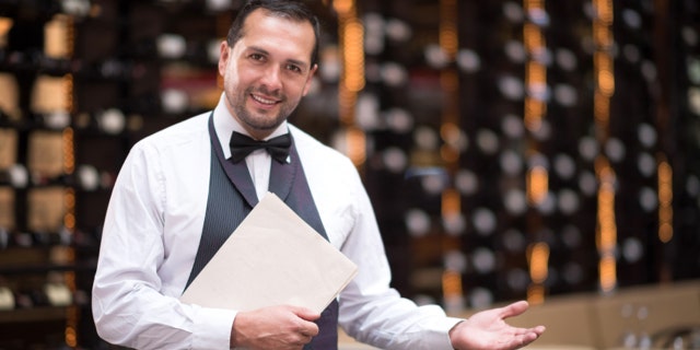 Friendly elegant waiter welcoming people to a restaurant