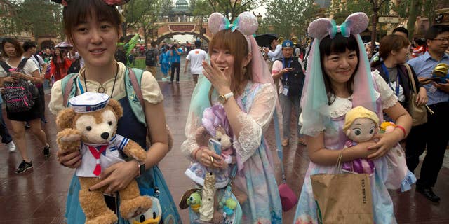 Visitors dress up as they attend the opening day of the Disney Resort in Shanghai, China, Thursday, June 16, 2016.
