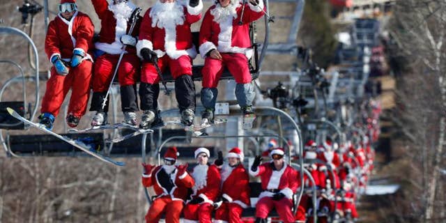 Skiers and snowboarders dressed as Santa ride a chairlift while participating in Santa Sunday at the Sunday River ski resort.