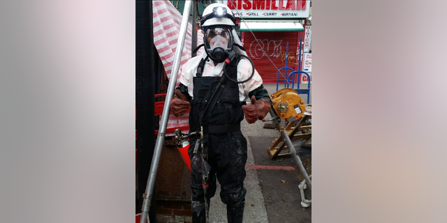 A workman in protective clothing prepares to go into the sewer.
