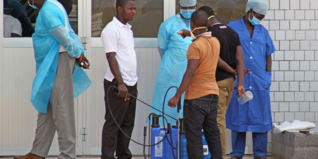 FILE - In this March 29, 2014, file photo, medical personnel at the emergency entrance of a hospital wait to receive suspected Ebola virus patients in Conakry, Guinea.