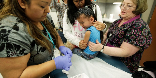 Nurses give a 4-year-old girl a Tdap whooping cough booster shot. (AP Photo/Ted S. Warren)