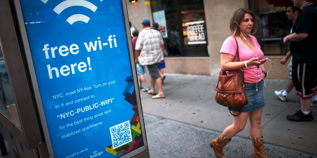 A woman walks past a WiFi-enabled phone booth in New York, July 12, 2012.