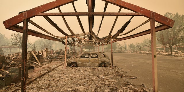 Burned out vehicles are surrounded by smoldering rubble while firefighters continue to battle the Valley fire in Middletown, California on September 13, 2015