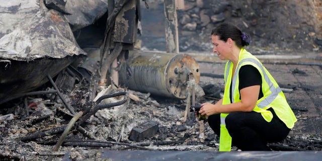 A woman looks at the charred remains of her mobile home after it was destroyed by a wildfire in the Alpine Oaks Estates where she has lived for more than eight years, in Alpine, Calif., Saturday, July 7, 2018.