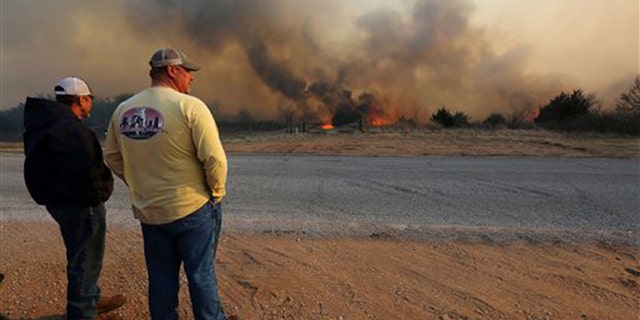 Jeff Clark and Roger Van Rankin watch the fire east of Lake City, Kan., Wednesday, March 23, 2016. The two were watching to see if the fire would jump the road onto Clark's ground.