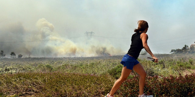 Apr. 30, 2014: A resident talks on her phone as she watches the Etiwanda Fire in Rancho Cucamonga, Calif.