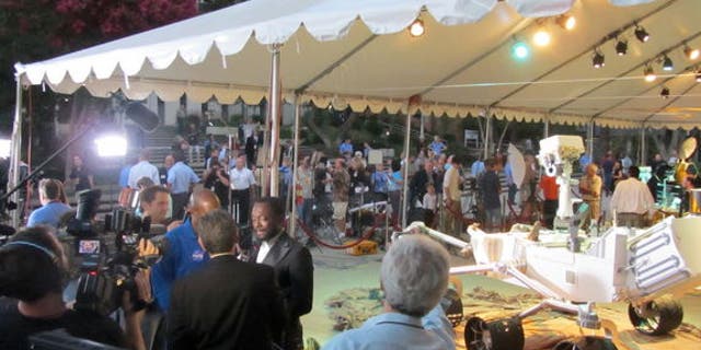 Musician will.i.am (center left) conducts an interview in front of a full-size model of the Curiosity rover on Aug. 5, 2012.