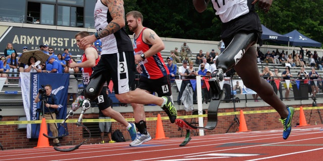 In this Thursday, June 16, 2016 photo, William Reynolds, right, a 2002 graduate of the U.S. Military Academy, competes in the 800-meter race at the Warrior Games in West Point, N.Y. Reynolds said his training and discipline are the same as when he was a competitive gymnast as a West Point cadet. The big adjustment was learning to run when he didnât have the sensation of his left foot hitting the ground anymore. (AP Photo/Mike Groll)