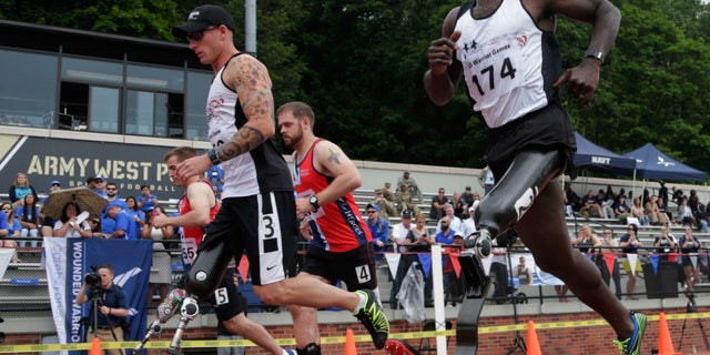 In this Thursday, June 16, 2016 photo, William Reynolds, right, a 2002 graduate of the U.S. Military Academy, competes in the 800-meter race at the Warrior Games in West Point, N.Y. Reynolds said his training and discipline are the same as when he was a competitive gymnast as a West Point cadet. The big adjustment was learning to run when he didnât have the sensation of his left foot hitting the ground anymore. (AP Photo/Mike Groll)