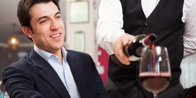 Waiter pouring wine to a customer