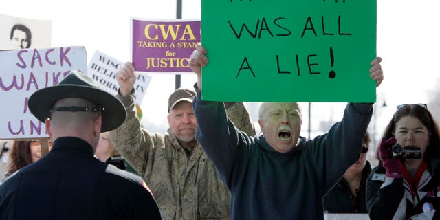 Dan Schierl of Neenah, Wis., second from right, joins other protesters during Gov. Scott Walker's announcement from the Fox Cities Trestle Trail over Little Lake Butte Des Morts Thursday, March 31, 2011 in Menasha, Wis. (AP)