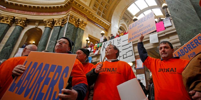 Union worker Dan Burke, center, of Janesville, Wis., uses a bucket to drum after loosing his voice during protests at the state Capitol in Madison, Wis., Friday, Feb. 25, 2011, over the governor's proposed budget. (AP)