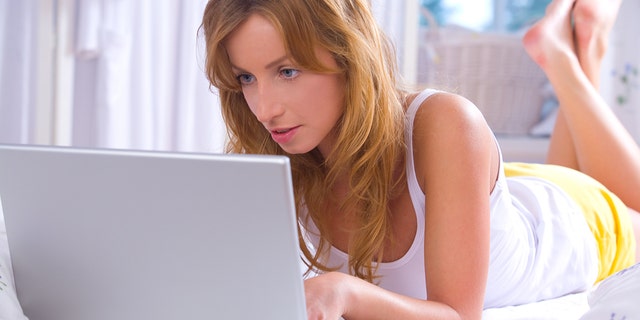 Young woman working with her laptop in bed