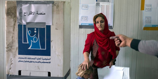 A volunteer points out the place where a displaced woman from Sinjar can cast her vote in the parliamentary elections, at a polling site in a camp for displaced people outside Irbil, Iraq, Saturday, May 12, 2018.
