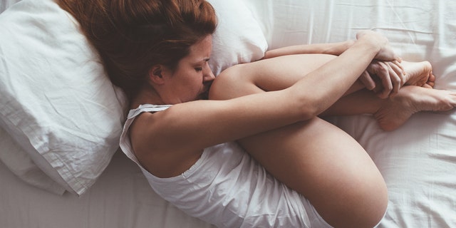 Young woman lying down in fetus position
