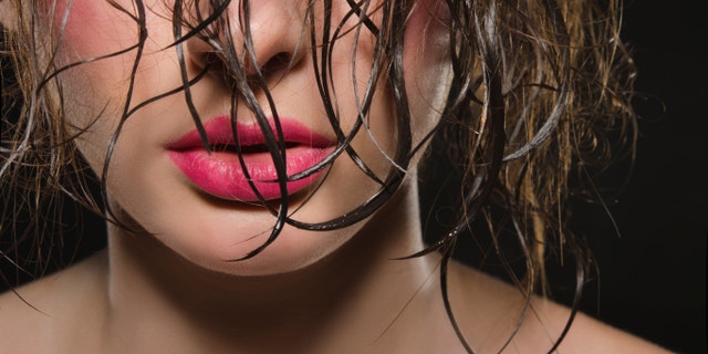 Portrait of beautiful woman with wet hair on dark background