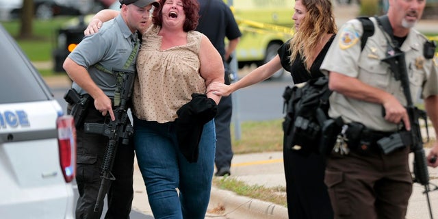 A women is escorted from the scene of a shooting at a software company in Middleton, Wis., Wednesday, Sept. 19, 2018.