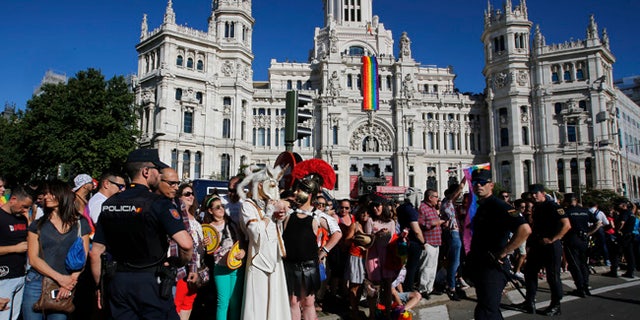 Participants and spectators mix in front of the City Hall with a rainbow flag hanging during the Gay Pride demonstration and parade, the climax of the 10-day WorldPride festivities, in Madrid, Spain, Saturday, July 1, 2017. Madrid is celebrating WorldPride 2017, a colorful mixture of vindication for sexual and gender diversity and all-night partying. (AP Photo/Paul White)