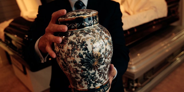 NEW YORK - NOVEMBER 20: Funeral director Peter DeLuca, owner of Greenwich Village Funeral Home, holds a cremation urn in the showroom of his funeral parlor on November 20, 2008 in New York City. New technologies, such as flat screen televisions for video memorials, ornate and even sports-team themed cremation urns are also slowly being introduced at funeral homes. Despite the currently languishing economy, the funeral home world is readying for an upswing nationally, as the recession-resistant business prepares for an expected rise in death rates as baby boomers start to reach old age in the coming decade. (Photo by Chris Hondros/Getty Images)