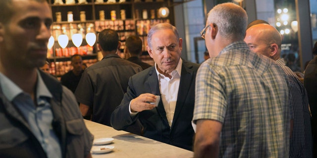 Israeli Prime Minister Benjamin Netanyahu sits at the scene of Wednesday's shooting attack at a Tel Aviv restaurant, Thursday, June 9, 2016. Israel on Thursday imposed travel restrictions on tens of thousands of Palestinians and sent hundreds of additional troops into the West Bank in response to a deadly shooting at a popular Tel Aviv tourist spot, but as the nation's leaders vowed tough responses, they stopped short of taking wider scale military action. (AP Photo/Tomer Appelbaum) ISRAEL OUT