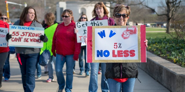 Elizabeth Ferguson Hollifield, a teacher from Princeton W.Va., holds a sign as she walks to a teacher rally Monday, March 5, 2018, at the West Virginia Capitol in Charleston, W.Va.