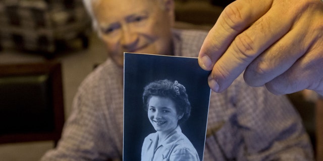 FILE - In this Nov. 6, 2015 file photo, Norwood Thomas, holds up a photo of with Joyce Morris at his home in Virginia Beach, Va. Thomas arrived in Australia Wednesday to reunite with Morris, his girlfriend during World War II. (Bill Tiernan/The Virginian-Pilot via AP)