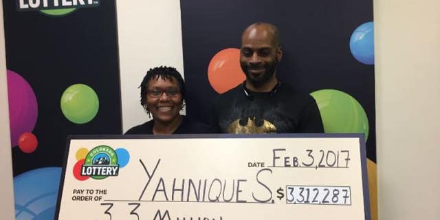 Yahnique, left, with her husband and their giant check.
