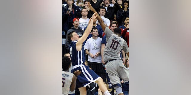 Yale's Jack Montague, left, shoots a game winning three-point shot over Connecticut's Sam Cassell Jr. (10) during the second half of Yale's 45-44 upset victory in an NCAA college basketball game in Storrs, Conn., on Dec. 5, 2014.