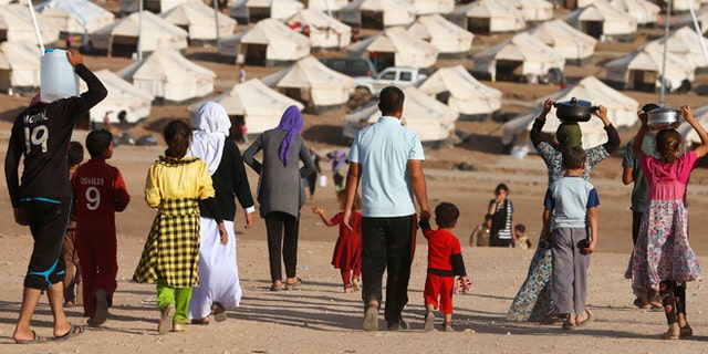 Aug. 22, 2014: Displaced people from the minority Yazidi sect, who fled violence in the Iraqi town of Sinjar, walk in Bajed Kadal refugee camp south west of Dohuk province
