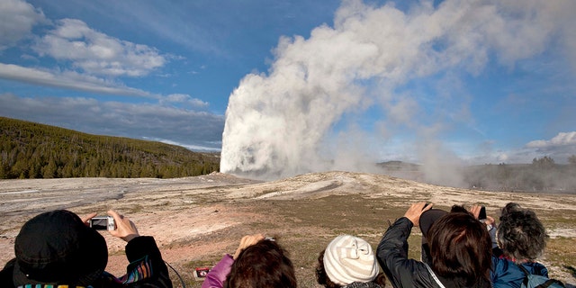 In this May 21, 2011, file photo, tourists photograph Old Faithful erupting on schedule late in the afternoon in Yellowstone National Park, Wyo.