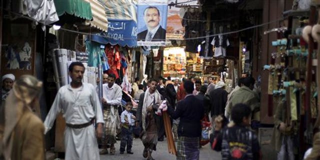 Aug. 9: People walk past vendors selling goods, beneath a poster showing Yemen's President Ali Abdullah Saleh, in a street leading to the old city of Sanaa, Yemen. The U.S. and Saudi Arabia pressured Yemen's president Ali Abdullah Saleh to stay in Saudi Arabia after he was released from a lengthy hospital stay to treat wounds suffered in an assassination attempt, according to Yemeni officials.