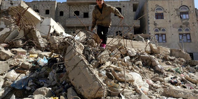 Sana'a. A child stands in the middle of destroyed buildings in his neighborhood.