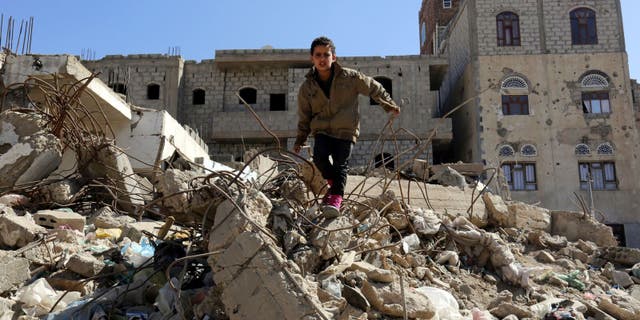 Sana'a. A child stands in the middle of destroyed buildings in his neighborhood.