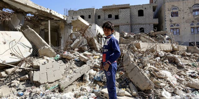 Sana'a. Ali, 13 years old, stands in the middle of destroyed buildings in his neighborhood.