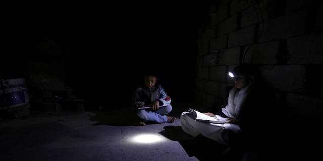 Sana'a. Intense darkness prevails over the neighborhood due to a severe shortage of electricity. Hisham, 14 years old, and Yazan, 8 years old, study in a room inside their home. E