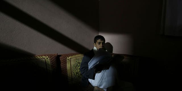 Sana'a. Intense darkness prevails over the neighborhood due to a severe shortage of electricity. Hisham, 14 years old, studies in a room inside his home.