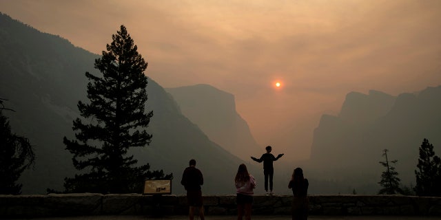 In this July 25, 2018 file photo, Hannah Whyatt poses for a friend's photo as smoke from the Ferguson fire fills Yosemite Valley in Yosemite National Park, Calif.