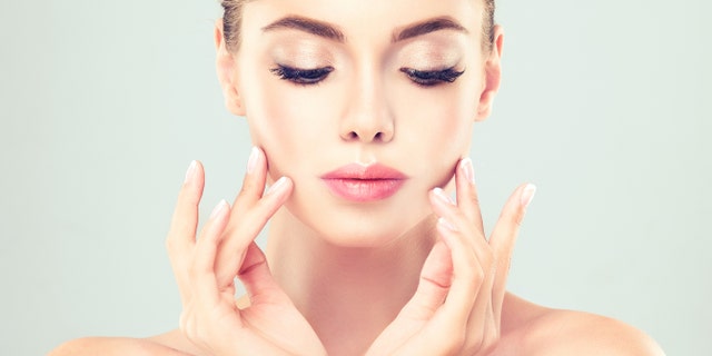 Close-up portrait of young woman with clean fresh skin. Make-up and manicure.