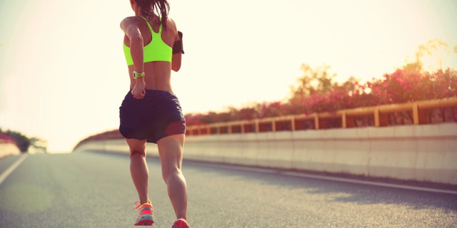 young woman runner running on city bridge road