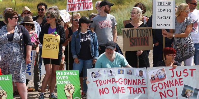 Protesters with colorful signs gather outside Trump's golf resort in western Scotland on Saturday.