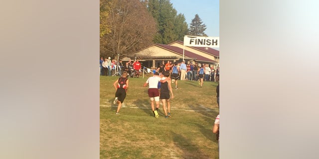 Seen from behind, Zach Hougland (left) helps Garret Hinson (right) walk toward the finish line.
