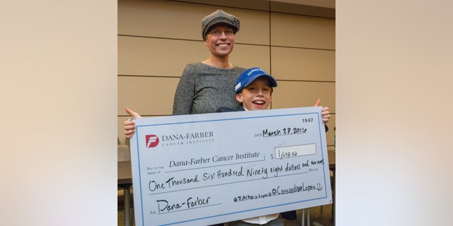 Zach Lopes and his mother, Christine, pose for a photo with the check Zach presented to the Dana-Farber Cancer Institute.