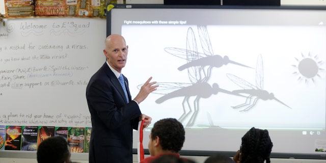 Florida Gov. Rick Scott talks with students who are studying the Zika virus, while visiting a classroom on the first day of school at the Jose de Diego Middle School, Monday, Aug. 22, 2016, in the Wynwood neighborhood of Miami. Mosquito-borne Zika cases have been found in an area of Wynwood, and in a section of Miami Beach. The CDC has issued an advisory for pregnant women to avoid travel to these two zones. (AP Photo/Lynne Sladky)