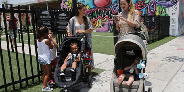 Vanessa Gomez, 33, left, with her son Ezra, 2, and her friend Cristy Fernandez, 33, with her 9-month-old- son River, of Miami, walk in the Wynwood neighborhood of Miami, Friday, July 29, 2016. Florida health officials said that four patients in Florida infected with the Zika virus were infected in the Wynwood area. These cases are believed to have caught the virus locally through mosquito bites. Gomez said the news is "scary but we cannot stop living our lives." To the left are Olivia Gomez, 5, and Kaly Fernandez. (AP Photo/Marta Lavandier)