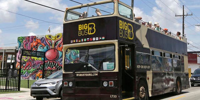 A tour bus makes a stop in front of the Wynwood Walls, Friday, Aug. 5, 2016, in the Wynwood area of Miami. Thank goodness it's the slow season in Florida. At least that's what officials and representatives of the state's $82 billion tourism industry are thinking in the wake of news that 15 people were infected with Zika in one small, trendy neighborhood in Miami. (AP Photo/Alan Diaz)