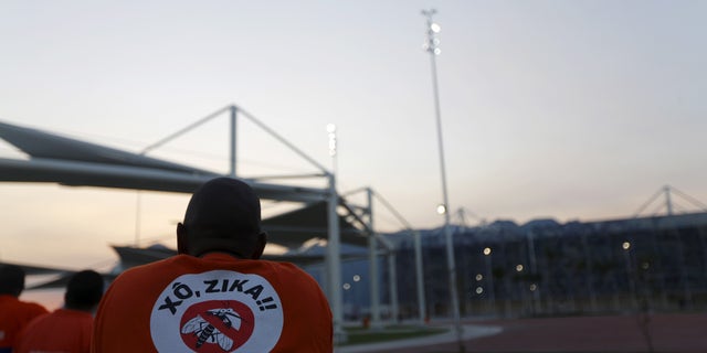 A worker from a public cleaning company wears a T-shirt that reads "Out Zika" is pictured before the inauguration ceremony of the common areas and the Live Site at the 2016 Rio Olympics park in Rio de Janeiro, Brazil, April 11, 2016.