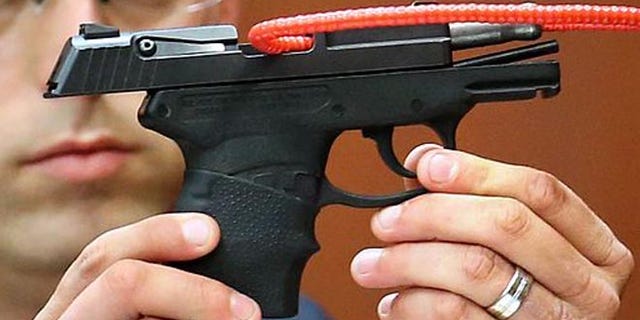 SANFORD, FL - JUNE 28: Sanford police officer Timothy Smith holds up the gun that was used to kill Trayvon Martin, while testifying on the 15th day of the George Zimmerman murder trial in Seminole circuit court June 28, 2013 in Sanford, Florida. Zimmerman is charged with second-degree murder for the February 2012 shooting death of 17-year-old Trayvon Martin. (Photo by Joe Burbank-Pool/Getty Images)