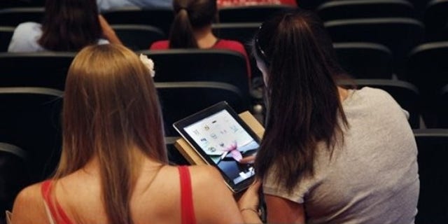 In this Aug. 23, 2011 photo, a student looks at her new iPad at Burlington High School in Burlington, Mass. Burlington is giving iPads this year to every one of its 1,000-plus high school students. Some classes will still have textbooks, but the majority of work and lessons will be on the iPads. (AP Photo/Elise Amendola)
