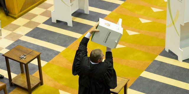 A parliamentary officer shows an empty ballot box to the South African parliament before voting for or against the motion of no confidence against South African president, Jacob Zuma in the South African parliament in Cape Town, South Africa, Tuesday, Aug. 8, 2017.